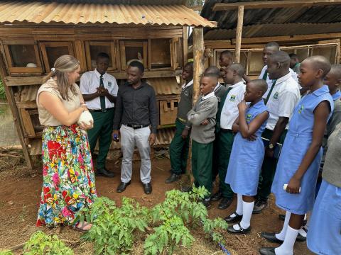 Researcher holding a white rabbit outdoors with a group of students.