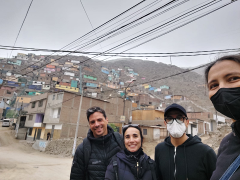 Four researchers standing in front of a Peruvian mountainside community.