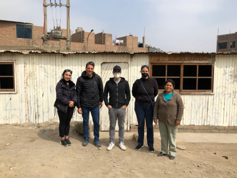 Five researchers standing in front of a small housing unit.