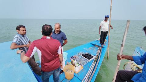 Researchers on a boat collecting water samples on Lake Chilika.