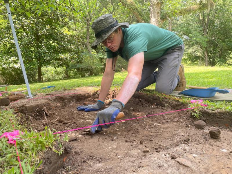 Archaeologist scrapes unit for artifacts.