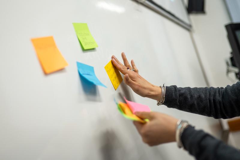 Colorful sticky notes being placed on white board.